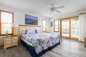 A bedroom with a bed, bedside tables, lamps, a ceiling fan, and large windows with curtains. - 2min Walk to Beach, Pool, Spa, Game Room, Big Yard (Corolla)