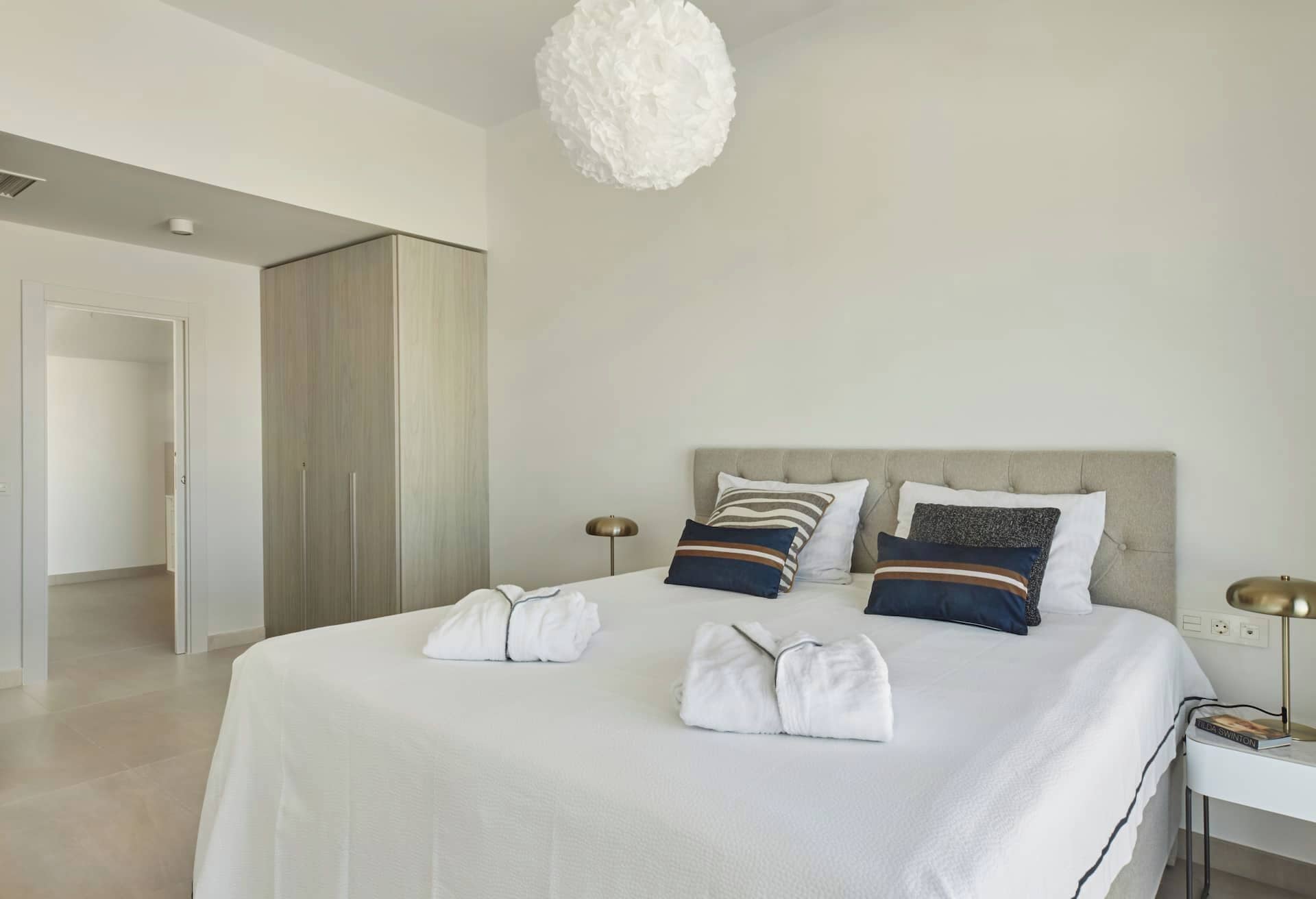 Ein Hotelzimmer mit einem großen Bett, einem Nachttisch mit Lampe und einem Kleiderschrank.