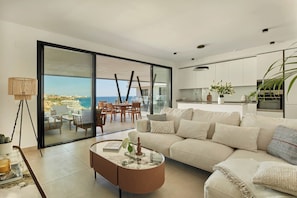 Un moderno salón con sofá, mesa de centro y vista al mar a través de un ventanal.