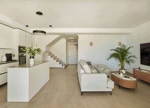 A modern living space with a kitchen, a sofa, a coffee table, and a staircase leading to another room. - Skyline Penthouse by IIM (Fuengirola)