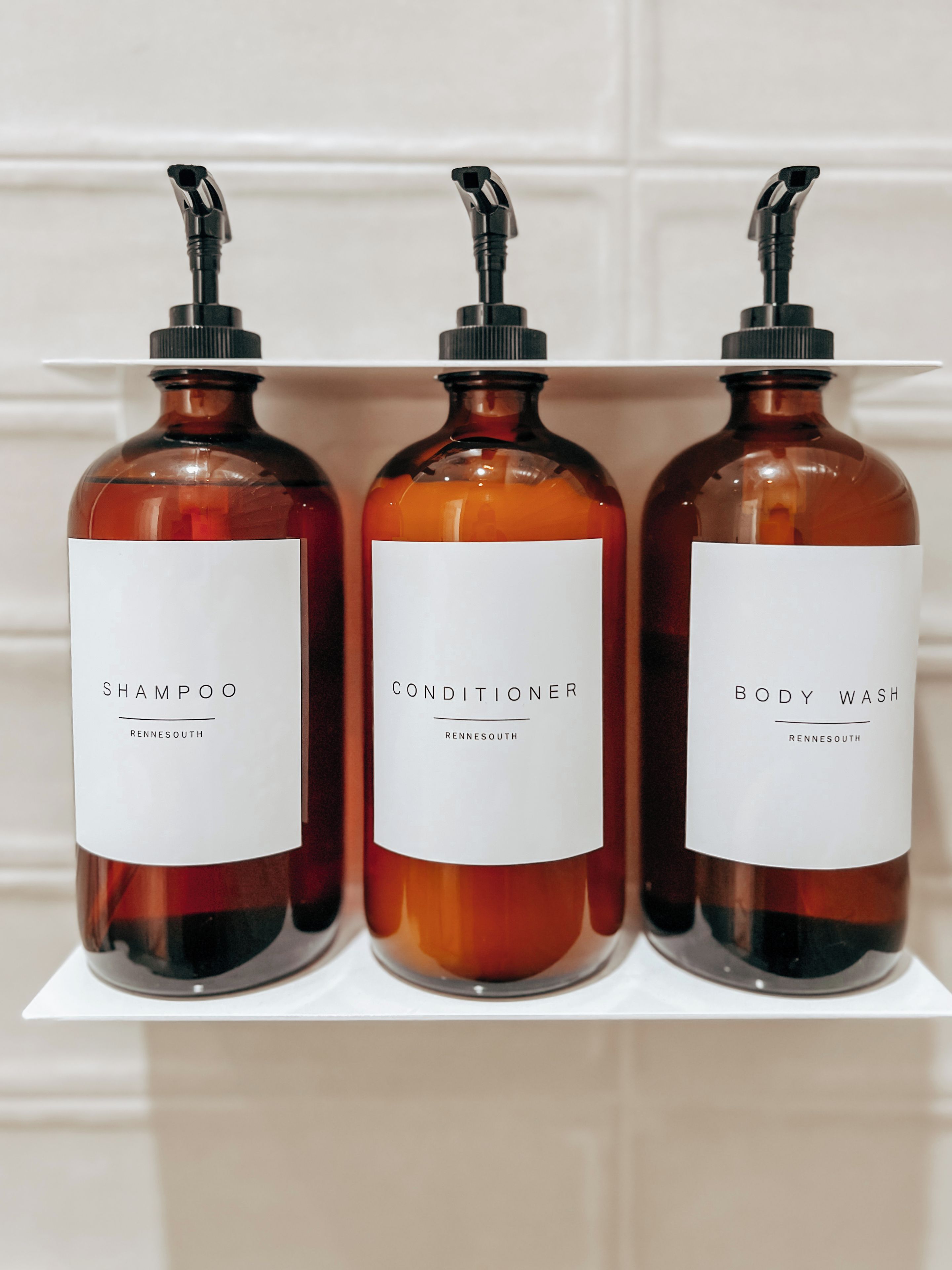 Three bottles of liquid on a shelf.