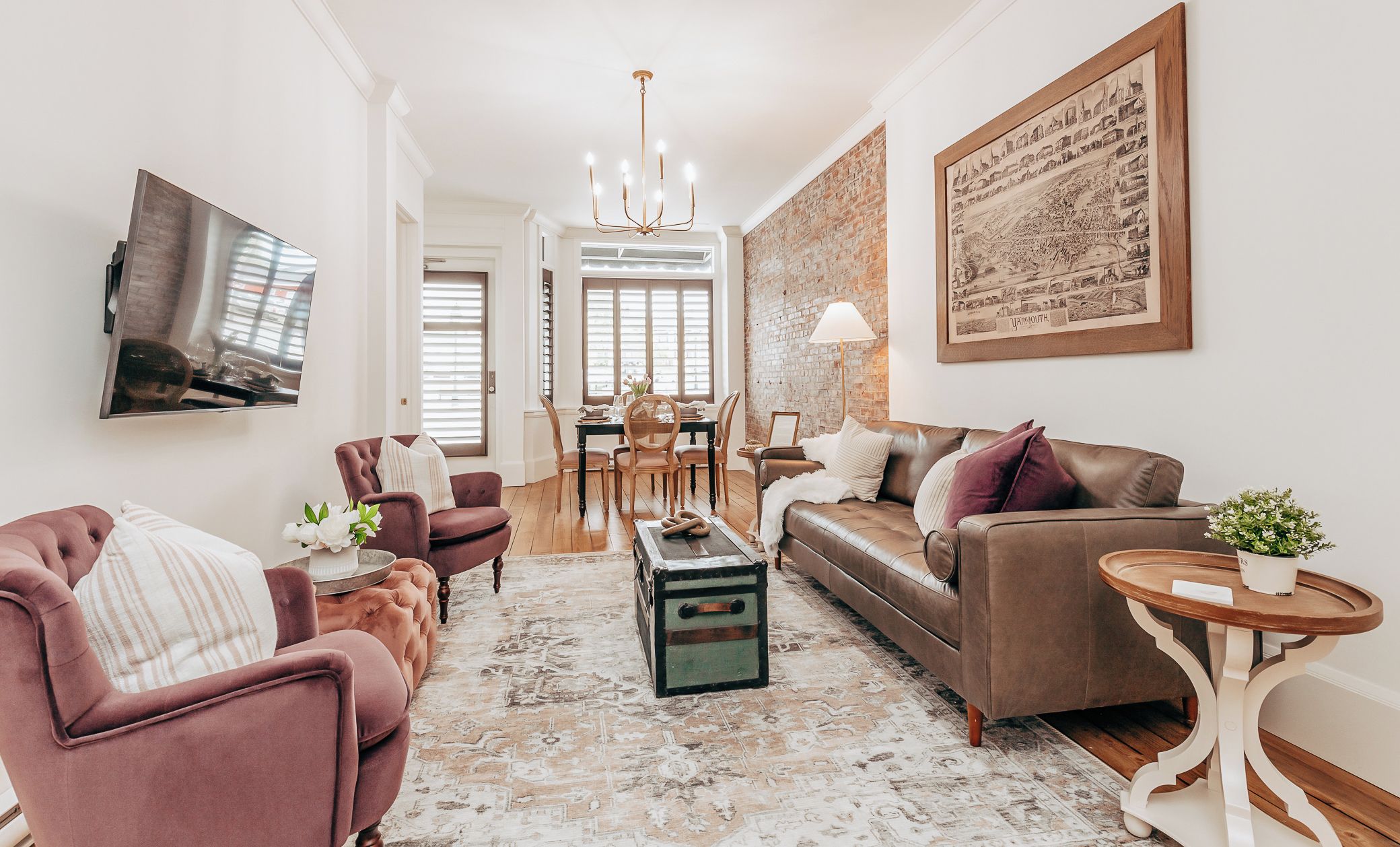 Un salon comprenant un canapé, des fauteuils, une table basse, un téléviseur et un coin repas avec une table et des chaises.