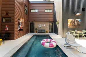 Ein Swimmingpool mit einem rosa und weißen Luftring, einer Couch und einem kleinen Tisch mit einer Pflanze.