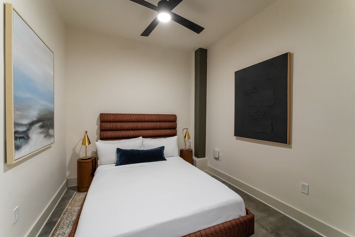 Ein Schlafzimmer mit einem Bett, einem Deckenventilator, zwei Nachttischen und Bildern an den Wänden.