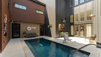 A modern building with a swimming pool, outdoor seating, and a mural.