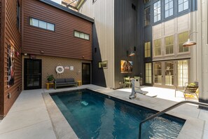A modern building with a swimming pool, outdoor seating, and a mural. - The Miss Lou (New Orleans)