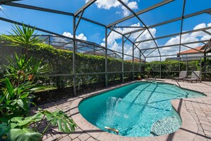 Ein Pool mit klarem, blauem Wasser, umgeben von einer Metallkonstruktion und üppiger Vegetation.