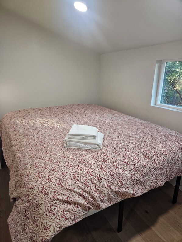 Una habitación con una cama, un ventanal y una lámpara en el techo.