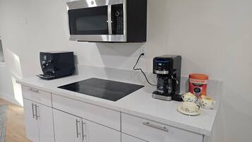 Een moderne keuken met een magnetron, koffiezetapparaat en een DUNKIN' N' DONUTS beker.