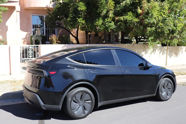 A black car parked on a street with a building and trees in the background. - Albuquerque Foothills Guesthouse near Trails: Pool Table, King Bed, Fast Wi-Fi (Albuquerque)