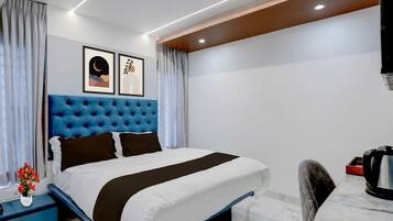 A modern hotel room with a large bed, a nightstand, a coffee maker, and artwork on the wall.