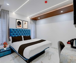 A modern hotel room with a large bed, a nightstand, a coffee maker, and artwork on the wall. - Classic Periyar Stay (Peermade)