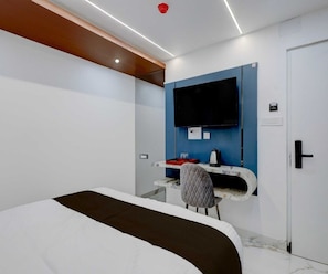 Una habitación de hotel moderna con una cama, un escritorio, una silla y un televisor montado en la pared.