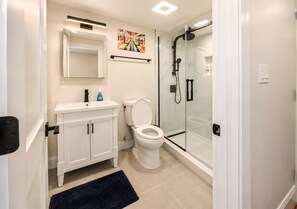A modern bathroom with a toilet, sink, and glass-enclosed shower. - 8-Beds Big Stay, 10Mins NYC, Free Reserved Parking (Jersey City)