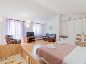 Ein Hotelzimmer mit Bett, einer Couch, einem Fernseher und einem Kleiderschrank.