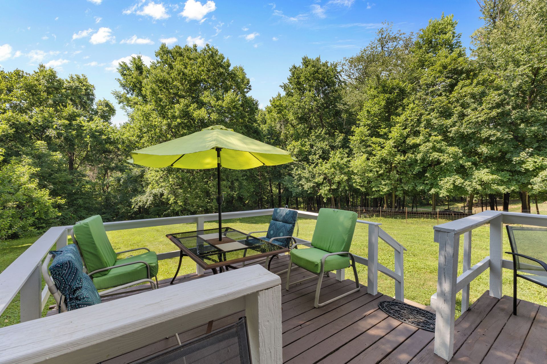 A deck with outdoor furniture, a table, and a green umbrella.