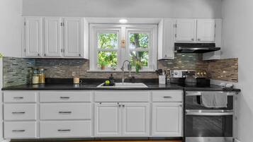 A modern kitchen with white cabinetry, a black countertop, and a stainless steel oven.