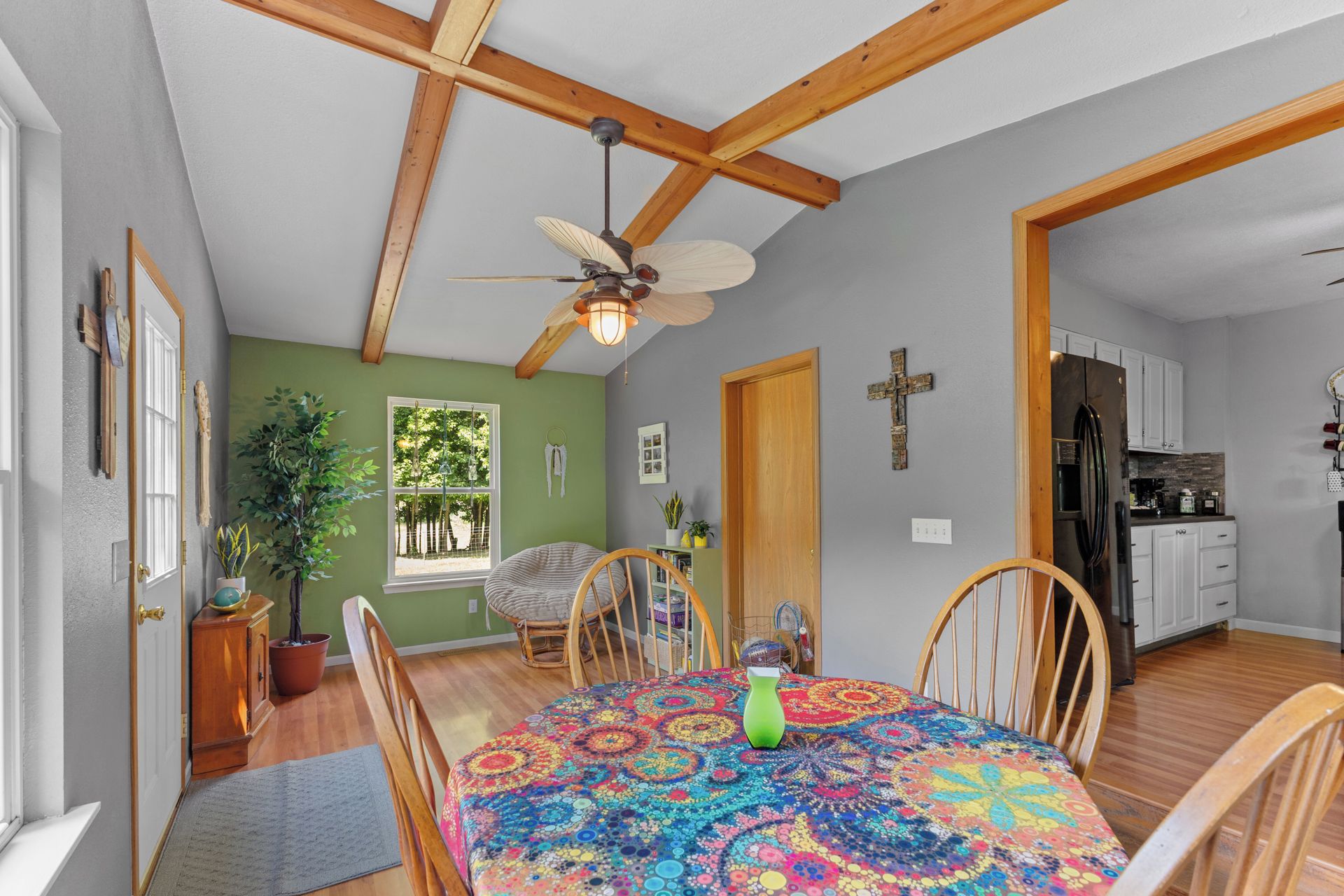 A dining area with a wooden ceiling, a ceiling fan, and a table with a colorful tablecloth.