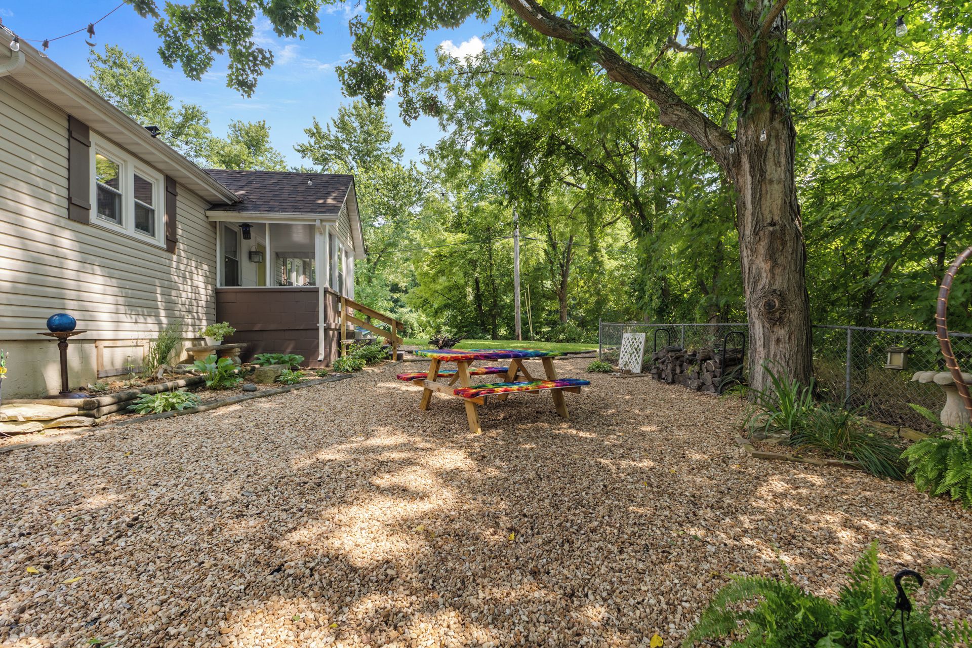A residential property with a covered porch, a gravel driveway, and a picnic table.