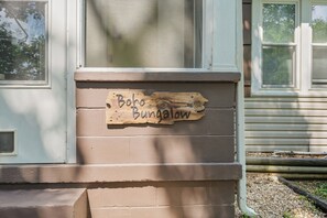 A wooden sign with the text 'Boh-Bungalow' mounted on a brick wall.