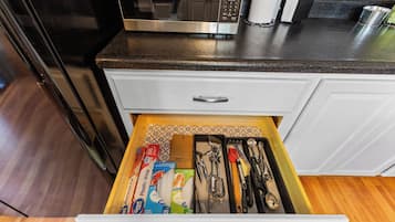 A kitchen drawer with various kitchen utensils and supplies.