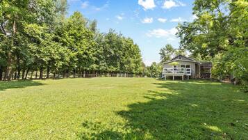A spacious grassy yard with a house featuring a porch and outdoor seating.