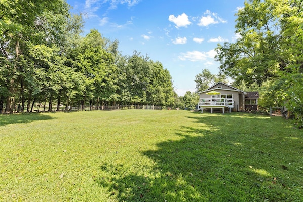 A spacious grassy yard with a house featuring a porch and outdoor seating.
