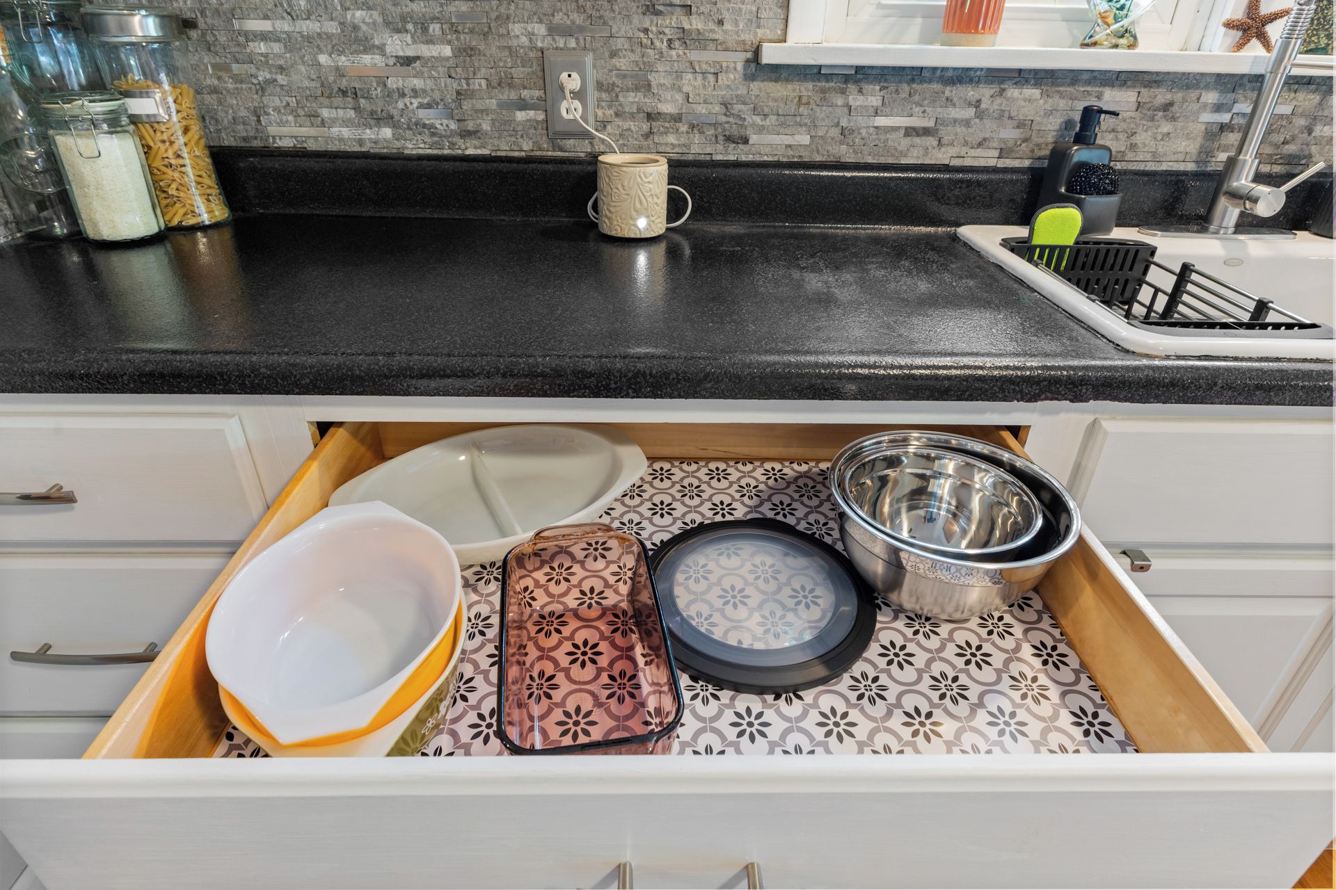 Un comptoir de cuisine avec une machine à café, une tasse et un flacon de savon pour les mains.