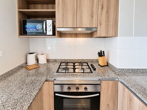 Una cocina moderna con microondas integrado, cocina a gas y horno.
