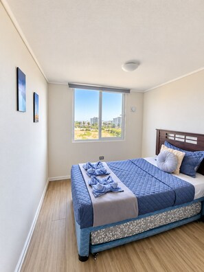 Ein Schlafzimmer mit einem großen Bett, einem Fenster mit Blick auf Gebäude und einem Holzboden.