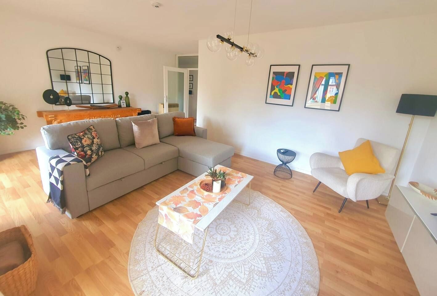 A living room with a sectional sofa, a round coffee table, and a white armchair.