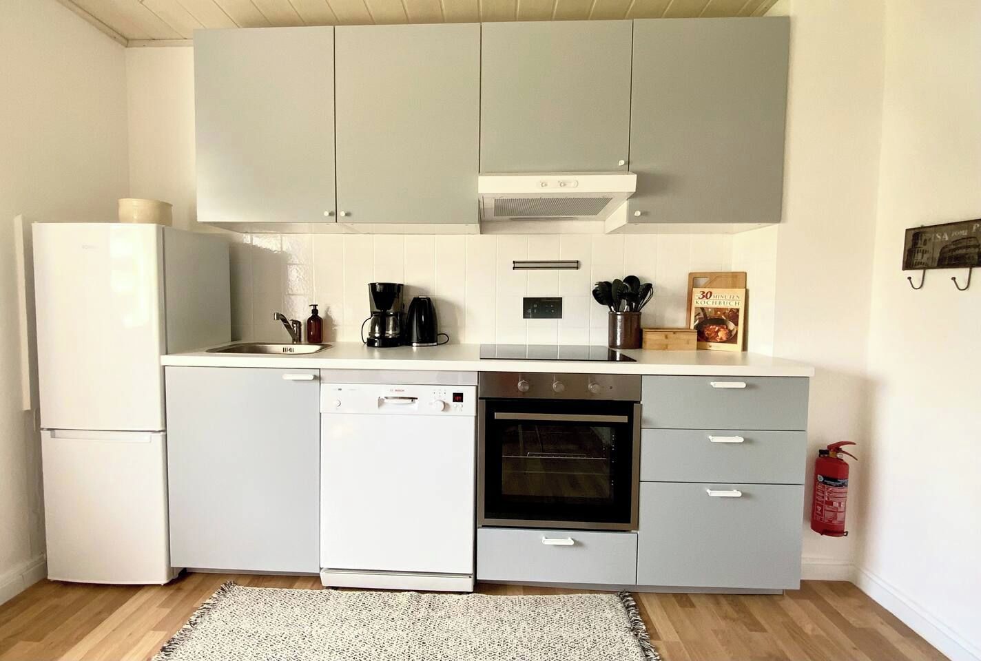 Eine kleine Küche mit Geschirrspüler, Backofen und Kaffeemaschine.