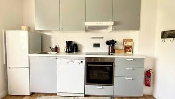 Eine kleine Küche mit Geschirrspüler, Backofen und Kaffeemaschine.
