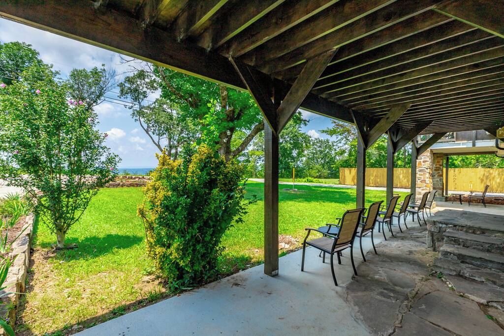 An outdoor patio area with a pergola structure, stone steps, and a row of chairs.