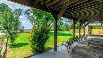 An outdoor patio area with a pergola structure, stone steps, and a row of chairs.