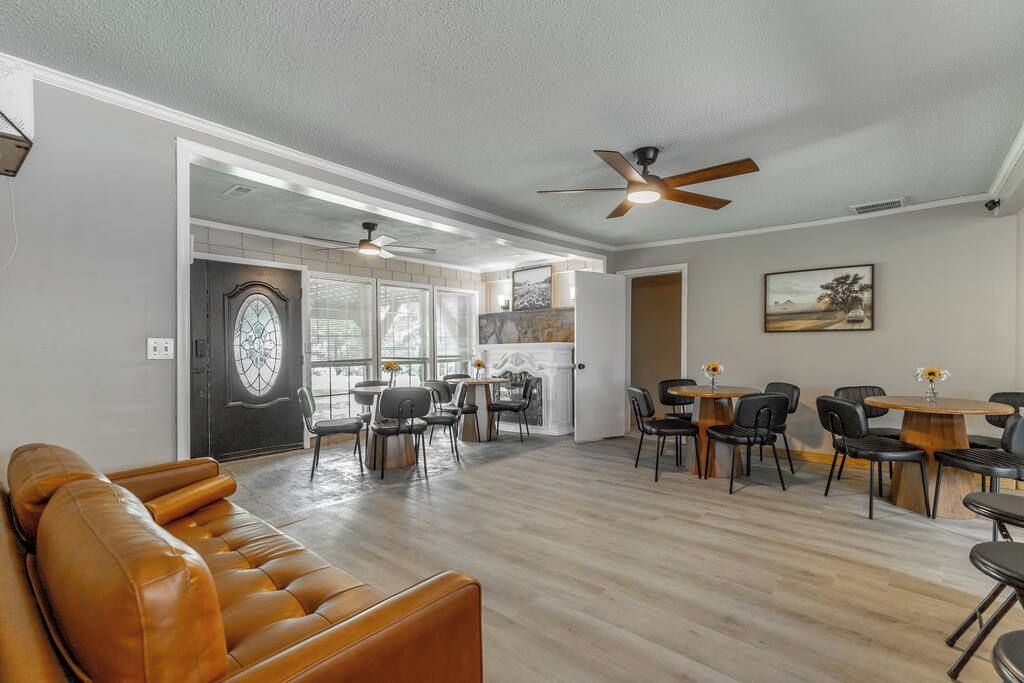 A spacious living area with a leather sofa, dining tables, and ceiling fans.
