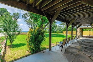 Ein Außenbereich mit Terrasse, einer Pergola, Steintreppen und einer Reihe von Stühlen.