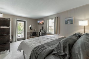 Ein Hotelzimmer mit Bett, Schreibtisch, Stuhl, Fernseher und Fenster.