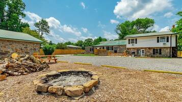 A stone building with a fire pit in the foreground, surrounded by mulch.
