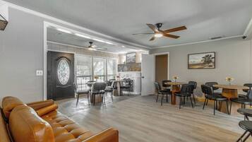 A spacious living area with a leather sofa, dining tables, and ceiling fans.