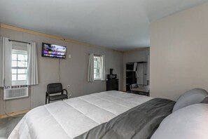 Ein Hotelzimmer mit einem großen Bett, einem an der Wand befestigten Fernseher, einem Schreibtisch und einem Kleiderschrank.