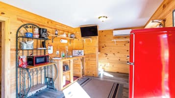 A compact kitchen with a red refrigerator, wooden walls, a microwave, and a small sink.