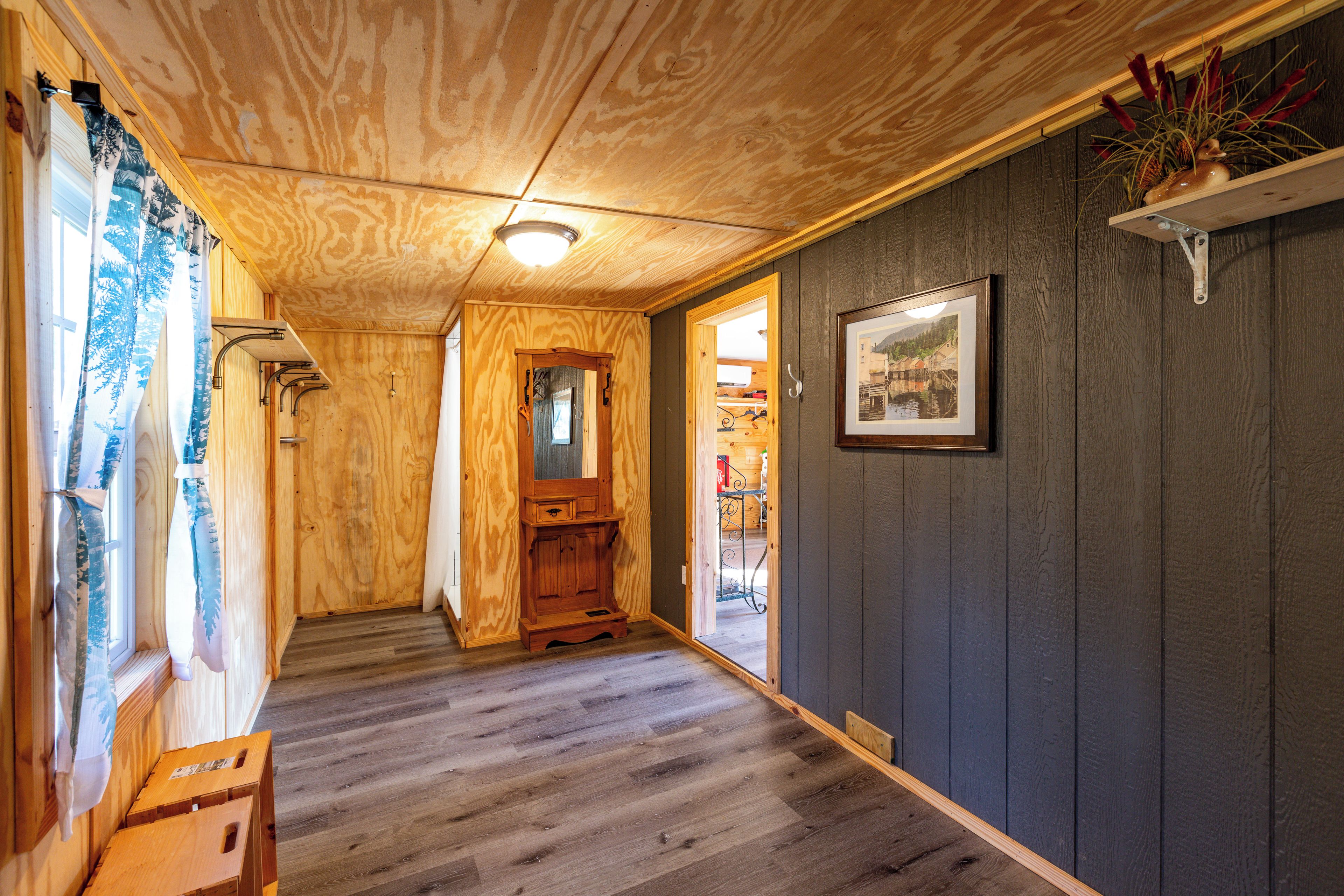 A wooden interior hallway with a wooden floor, a door leading to another room, and a framed picture on the wall.