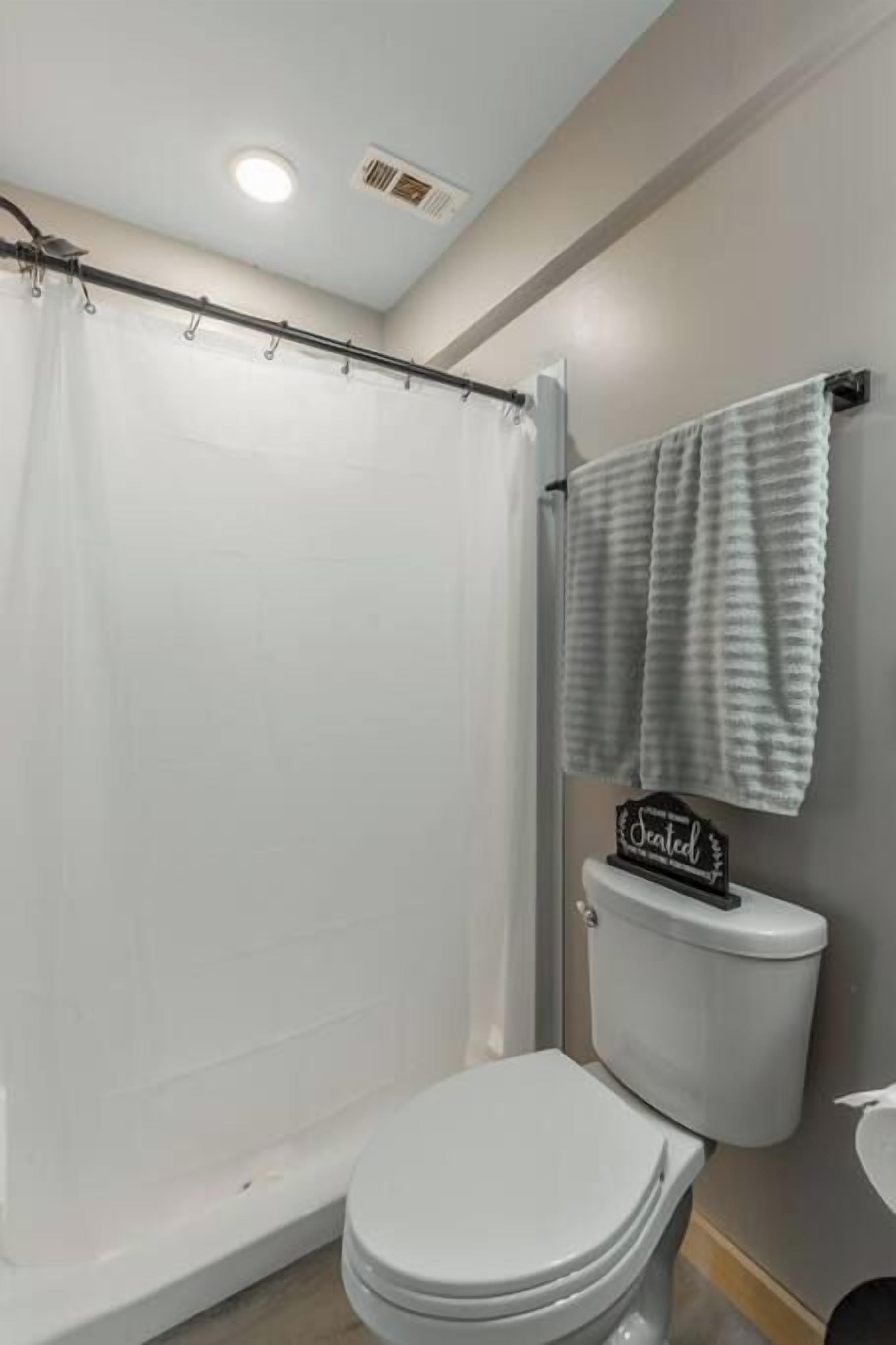 A bathroom with a shower curtain, a toilet, and a towel rack.
