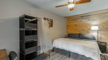 A bedroom with a bed, a ceiling fan, a wardrobe, and a bedside table.