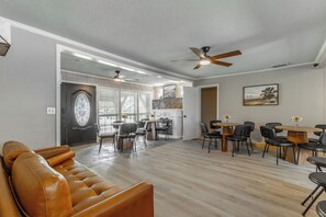 Ein großzügiger Wohnbereich mit Ledersofa, Esstischen, Stühlen und Deckenventilatoren.