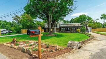 A residential property with a mailbox, a well-maintained lawn, and a large tree.
