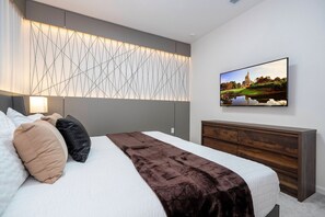 A modern hotel room with a bed, a wall-mounted TV, and a decorative panel. - 6BR Paradiso Grande Movie Theater & Pool (Orlando)