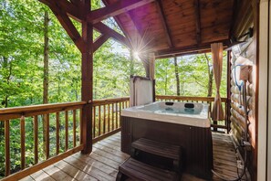 Une terrasse en bois avec un jacuzzi et un mur en pierre.