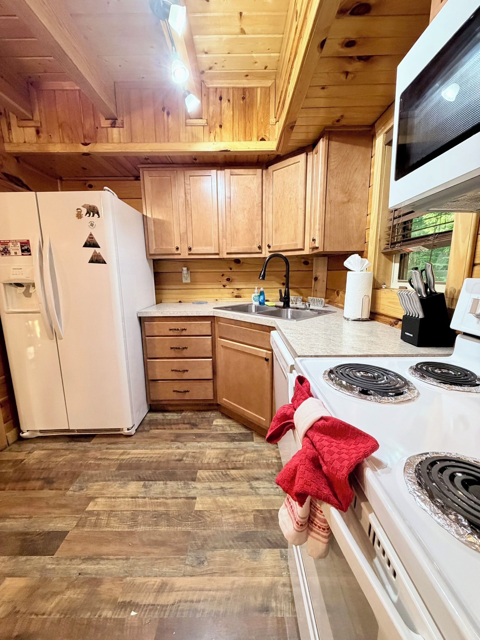 A kitchen with wooden cabinets, a refrigerator, a stove, and a sink.